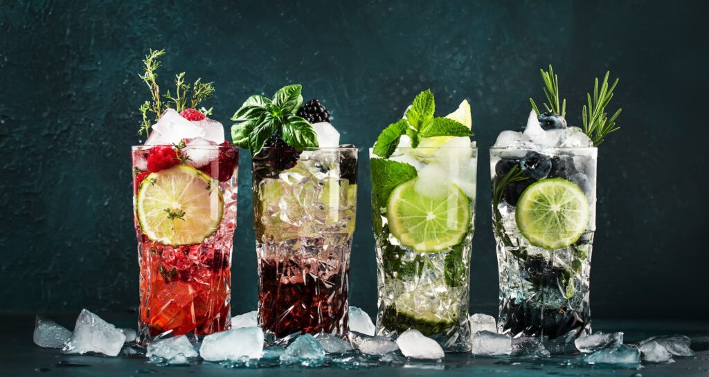 Cocktails drinks. Classic alcoholic long drink or mocktail highballs with berries, lime, herbs